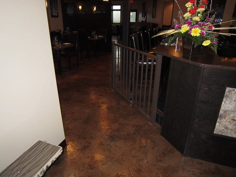 Image of a restaurant floor with an acid-stained flooring system. The flooring features a textured surface with natural variations in color and texture, creating a unique and rustic look for any restaurant.
