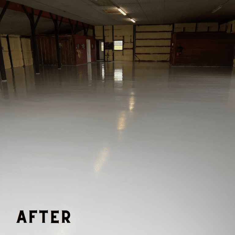 Image of a shiny, gray garage floor with a smooth surface and natural variations in color and texture. The Resinous Epoxy Flooring system has been applied to the garage floor, providing a durable and attractive surface.